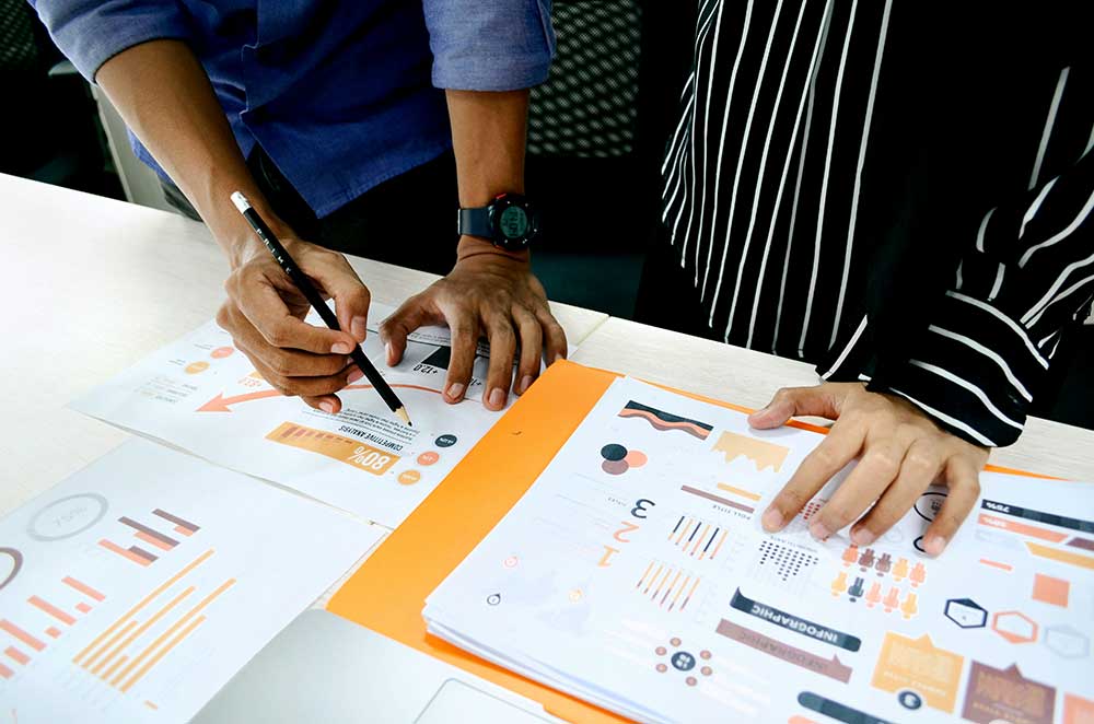 Marketing team reviewing printed budget charts and cost breakdowns